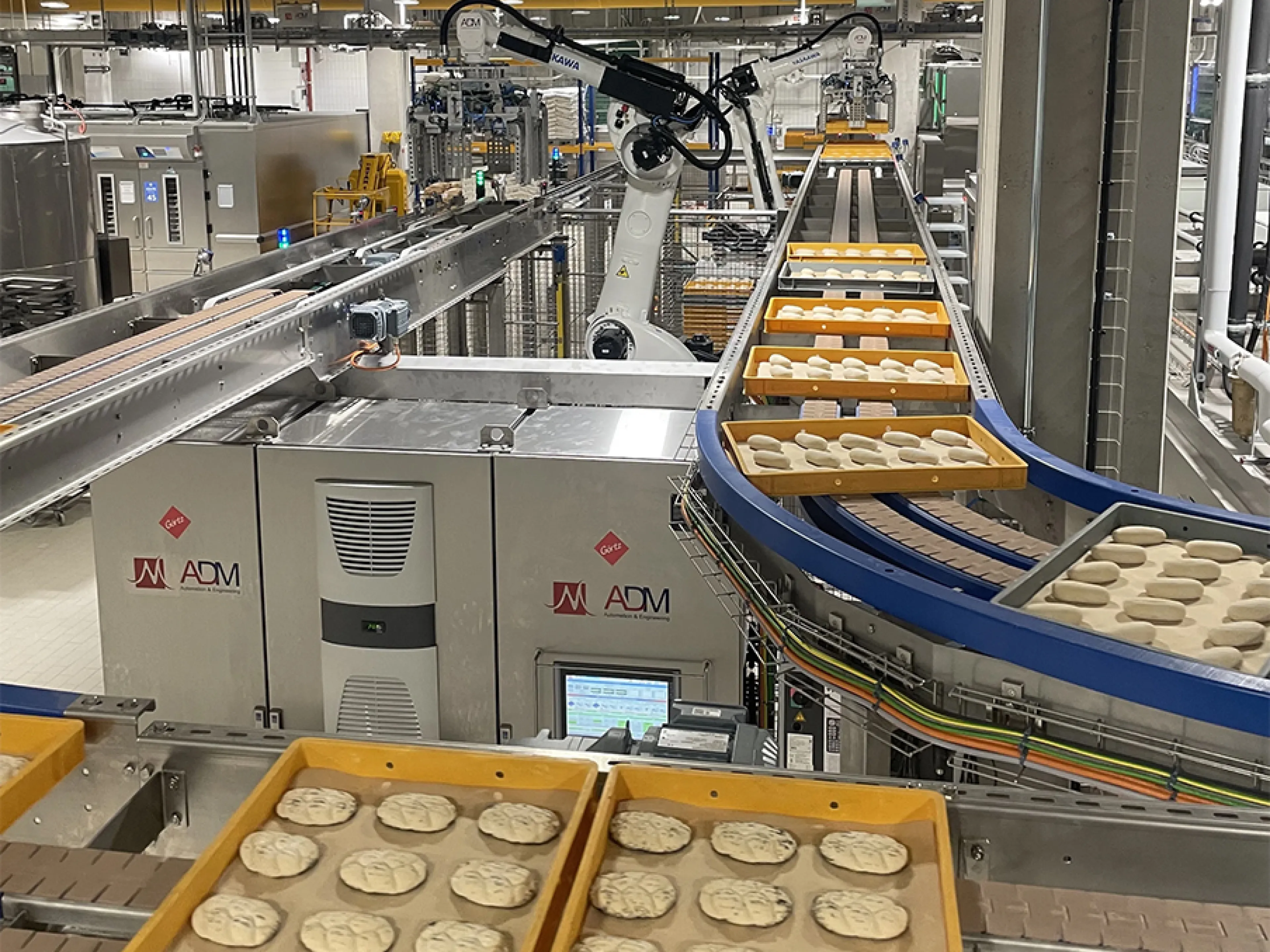 Zwei der vier „Motoman GP180“-Roboter von Yaskawa entnehmen die Dielen am Frosterauslauf und setzen sie auf ein Förderband um