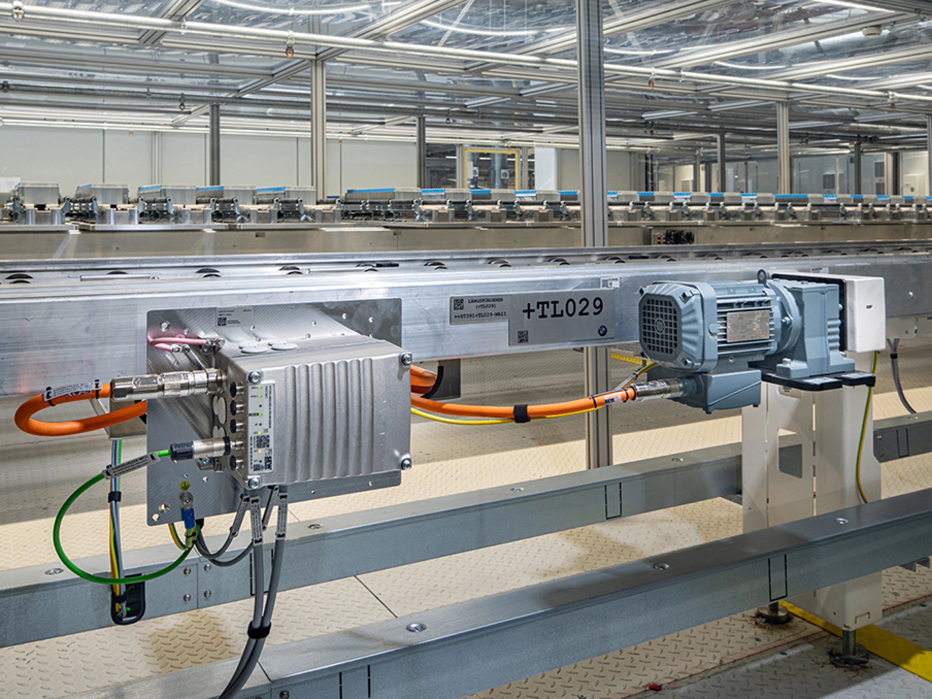 Die Batteriemodulproduktion ist mit Antriebstechnik von SEW-Eurodrive ausgestattet. Der dezentrale Umrichter Movimot flexible (li.) ist für die motornahe Installation vorgesehen. Er speist einen Stirnradgetriebemotor der Baureihe „R..DR..“ mittels Einkabeltechnik (orange). Über die digitale Motorschnittstelle „Movilink DDI“ werden Leistungs-, Bremsen- und Diagnosedaten übertragen.