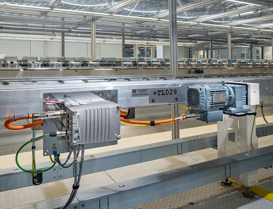 Die Batteriemodulproduktion ist mit Antriebstechnik von SEW-Eurodrive ausgestattet. Der dezentrale Umrichter Movimot flexible (li.) ist für die motornahe Installation vorgesehen. Er speist einen Stirnradgetriebemotor der Baureihe „R..DR..“ mittels Einkabeltechnik (orange). Über die digitale Motorschnittstelle „Movilink DDI“ werden Leistungs-, Bremsen- und Diagnosedaten übertragen. Ein Stirnradgetriebemotor „R..DR..“ treibt die horizontale Fördertechnik in der Pufferzone an, in der die Klebstoffe der Module aushärten, Bild: SEW-Eurodrive Die Batteriemodulproduktion ist mit Antriebstechnik von SEW-Eurodrive ausgestattet. Der dezentrale Umrichter Movimot flexible (li.) ist für die motornahe Installation vorgesehen. Er speist einen Stirnradgetriebemotor der Baureihe „R..DR..“ mittels Einkabeltechnik (orange). Über die digitale Motorschnittstelle „Movilink DDI“ werden Leistungs-, Bremsen- und Diagnosedaten übertragen.